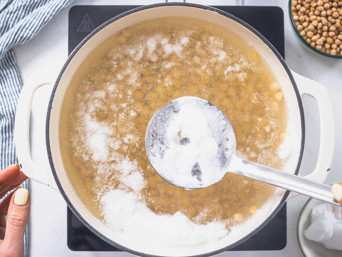 chickpeas cooking in a white pot with foam