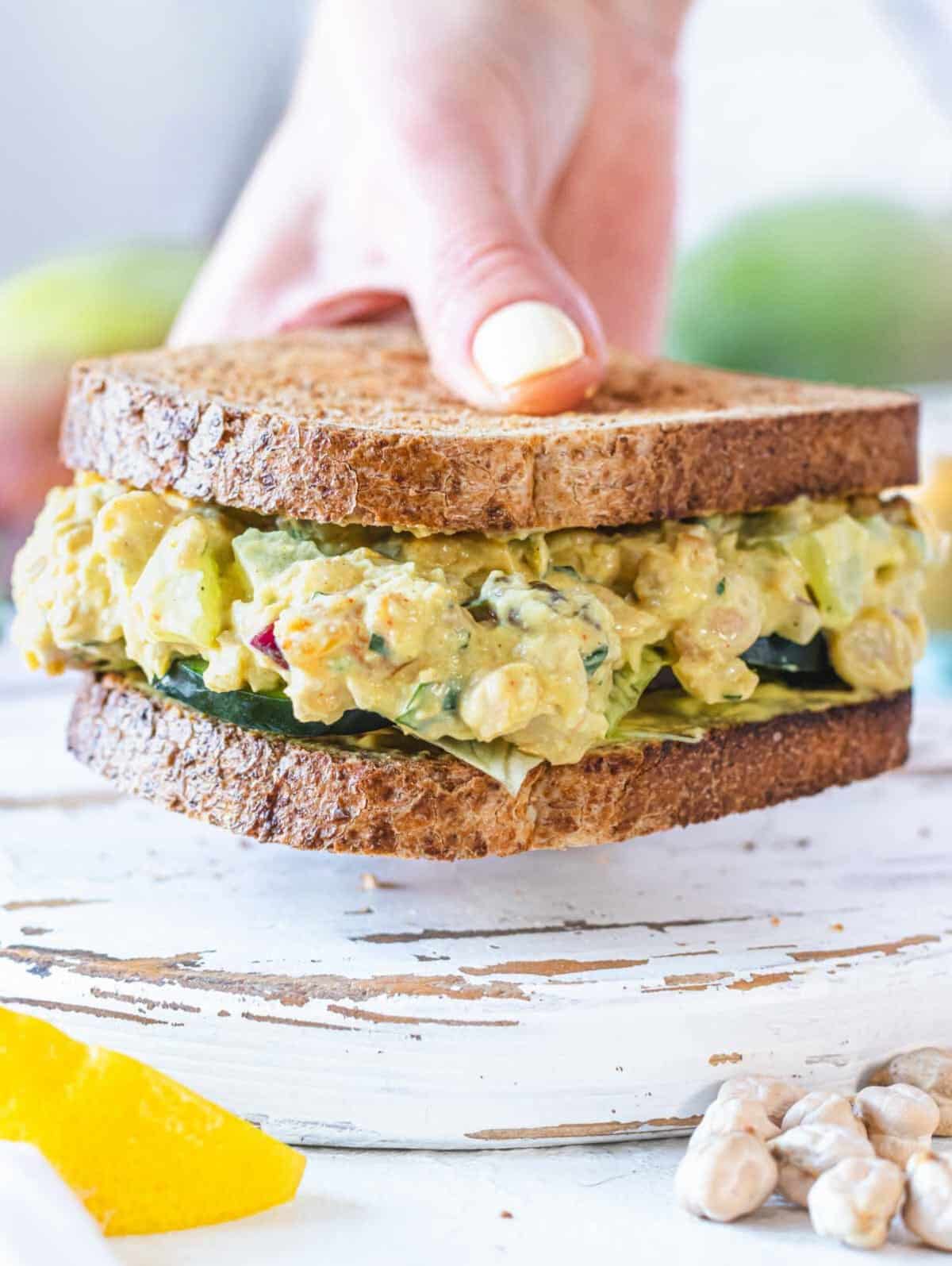 curry chickpea salad sandwich and a hand
