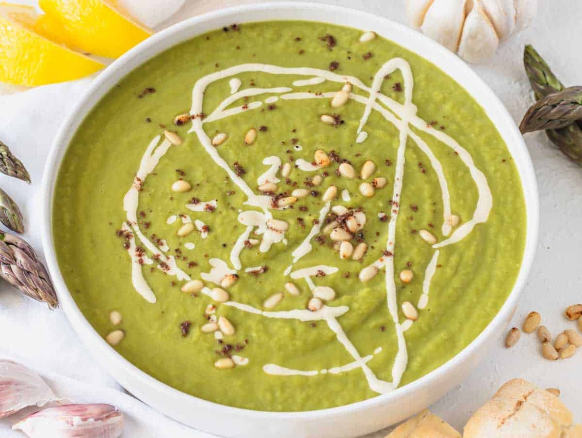 Asparagus soup with a drizzle of tahini sauce and toasted pine nuts