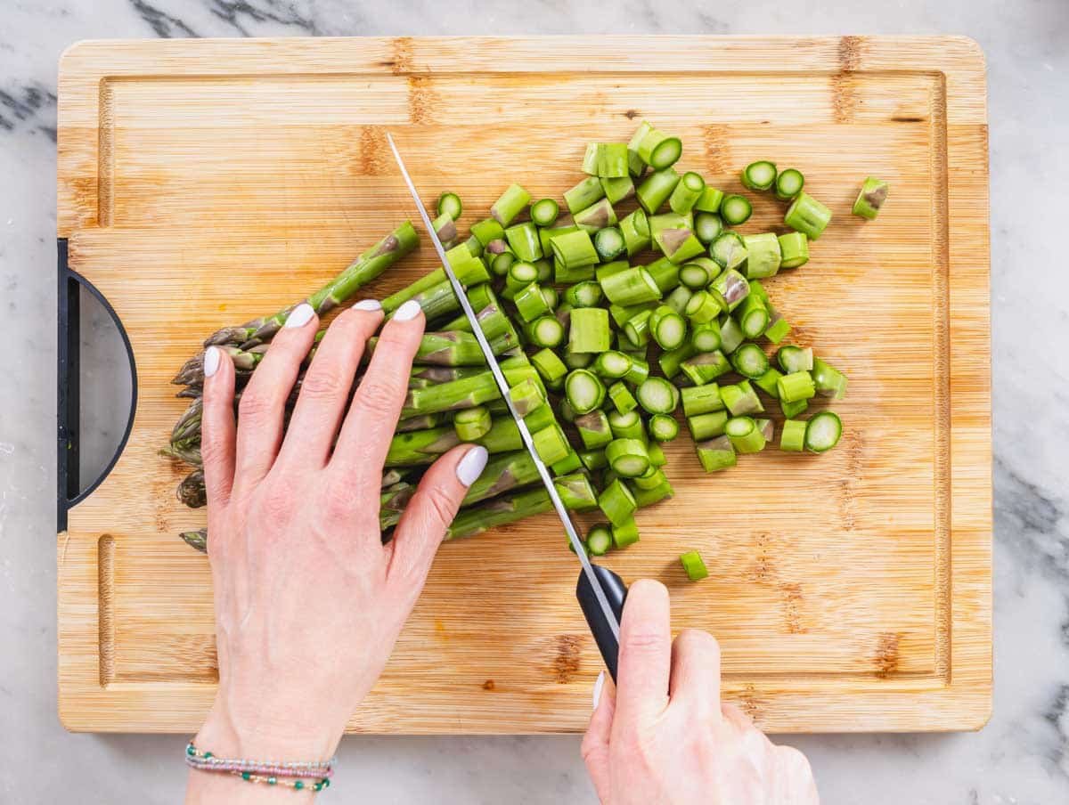 hand cutting asparagus into smaller pieces