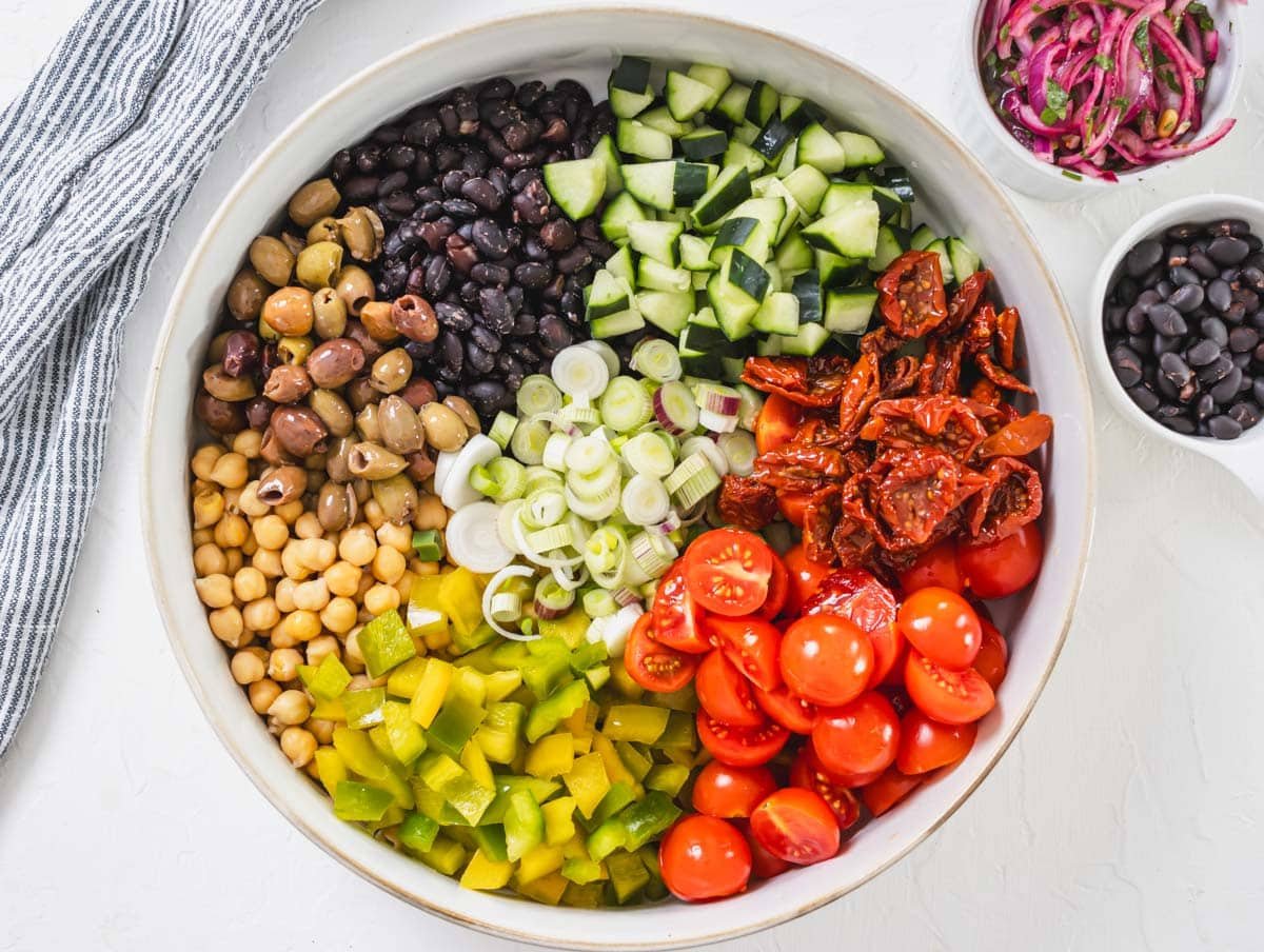 chopped vegetables, black beans and chickpeas in a white bowl