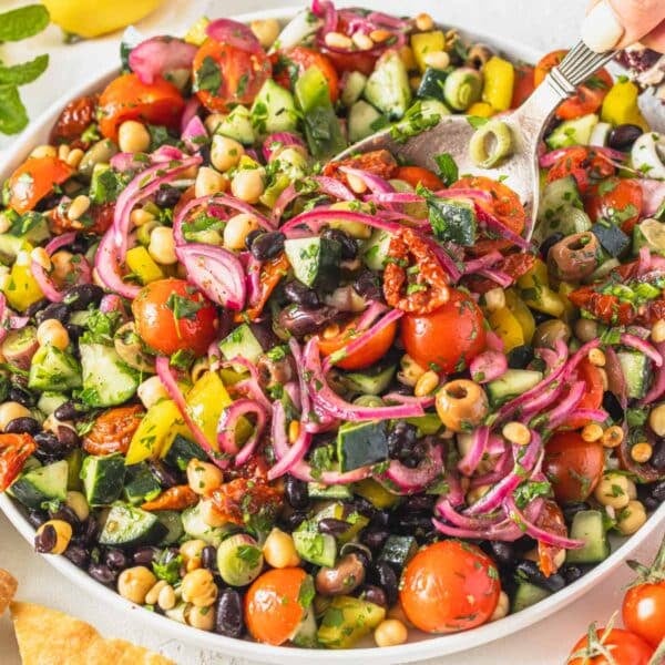 Mediterranean salad with olives, sundried tomatoes, and black beans on a white plate