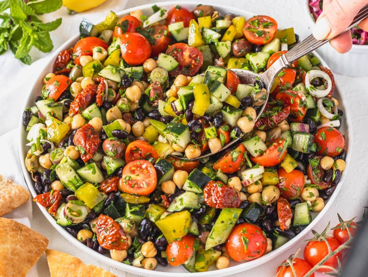 Mediterranean salad with chickpeas and black beans on a white plate