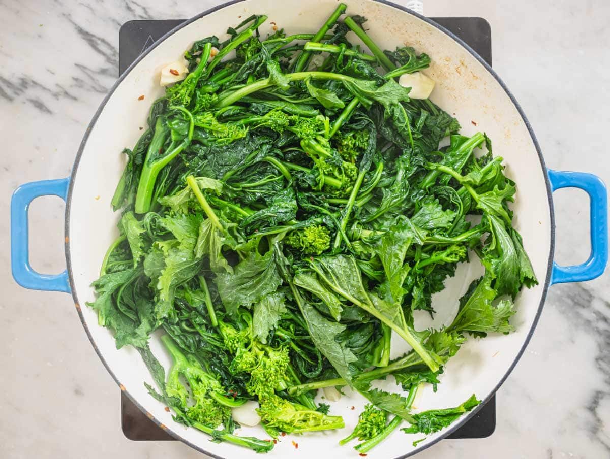 broccoli rabe cooking in a blue skillet