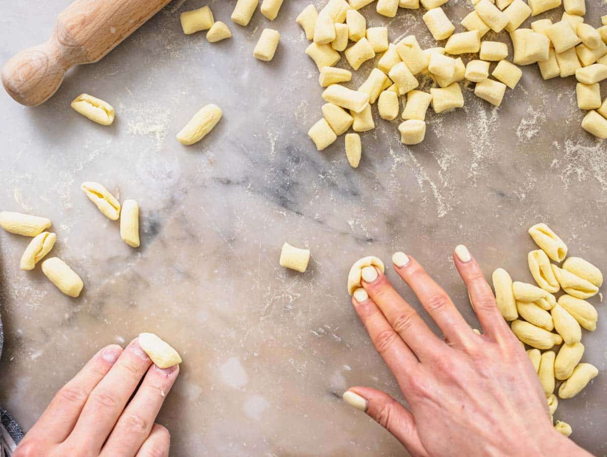 hands shaping cavatelli pasta on a worktop