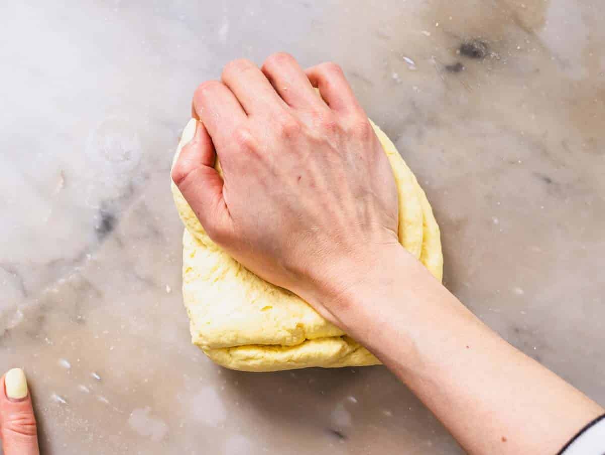 Hands kneading a semolina dough on marble surface