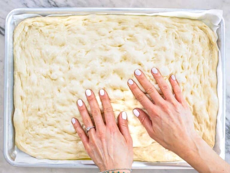 female hands touching dough on a baking tray
