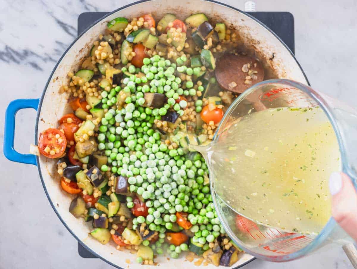 frozen peas and vegetable broth added to a skillet