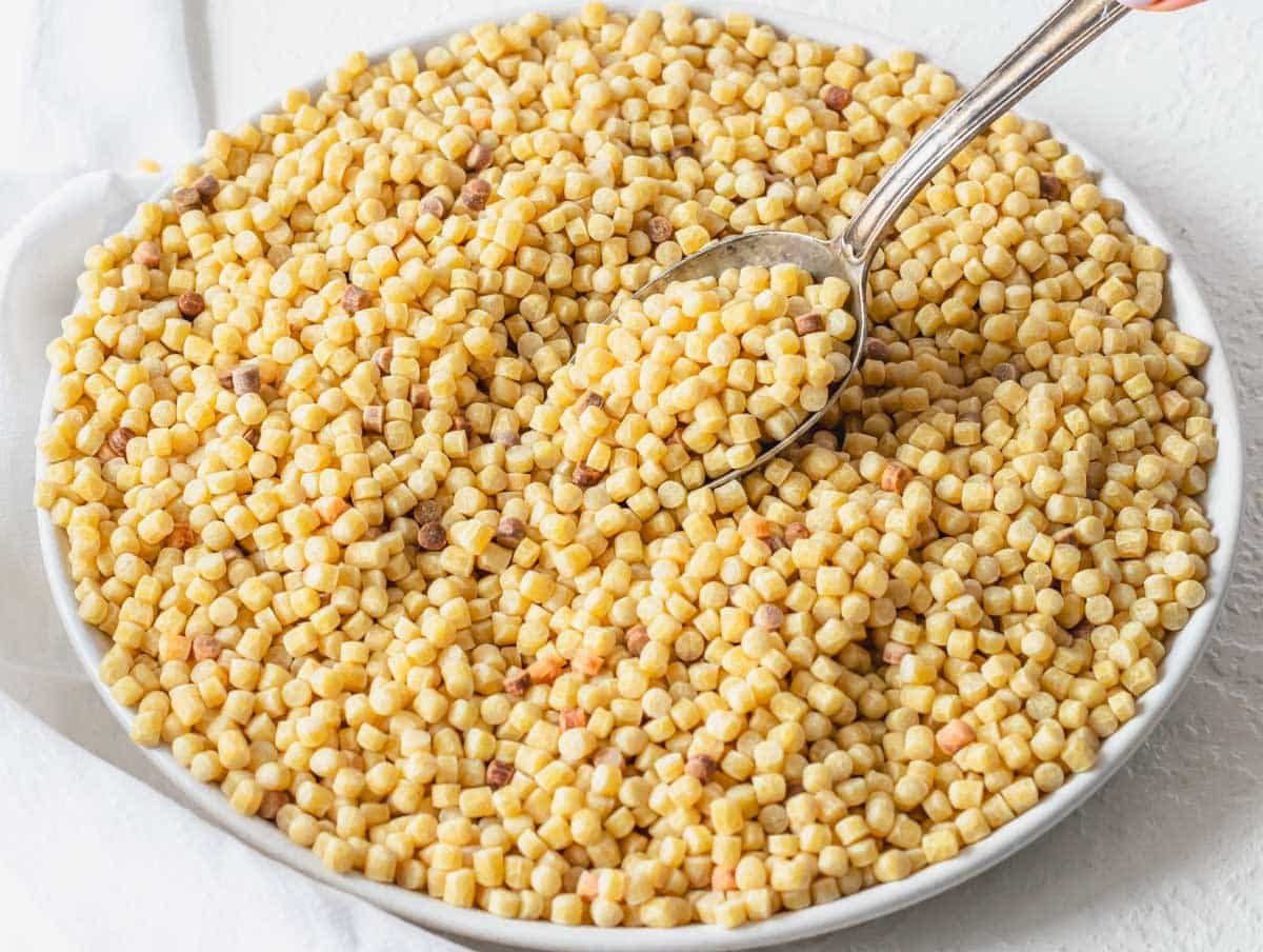 Fregola pasta on a white plate with a silver spoon