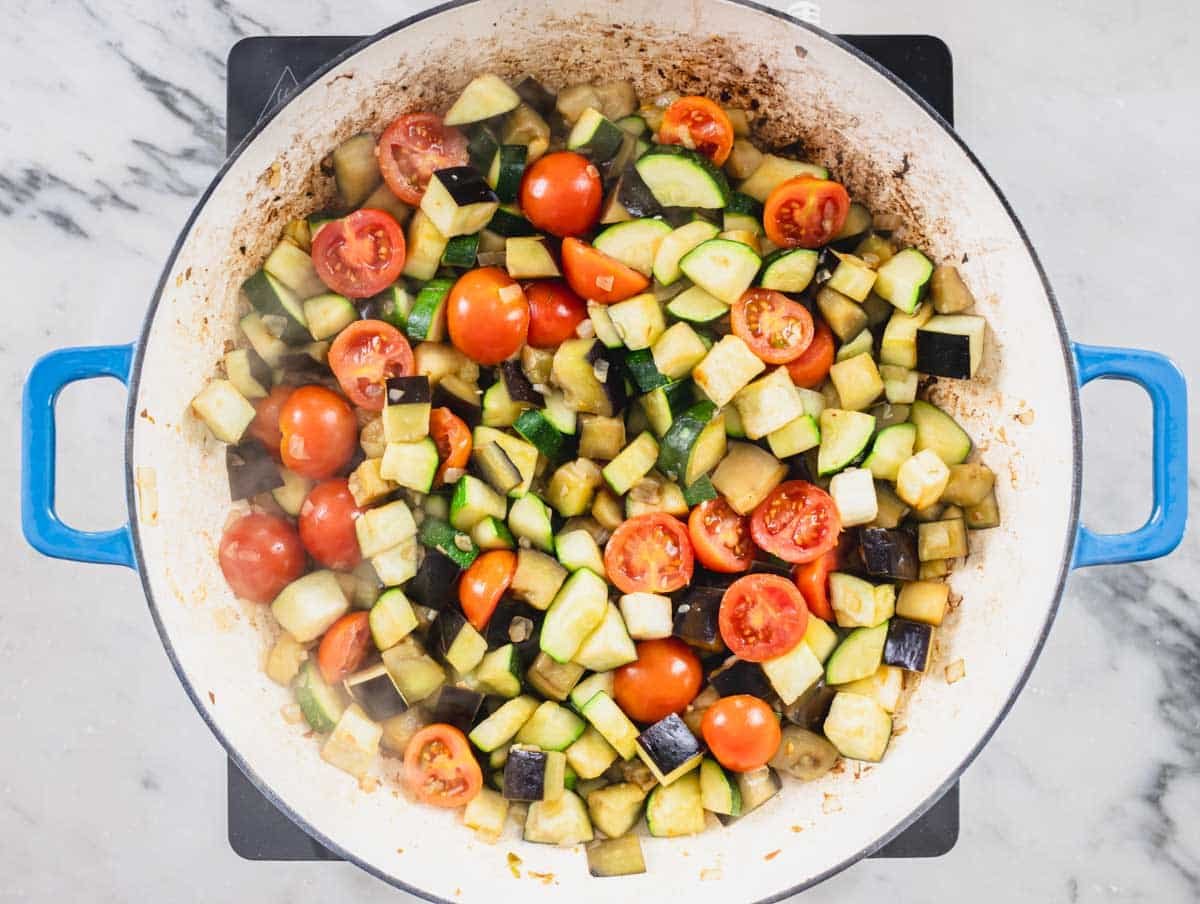 chopped vegetables added to a blue skillet
