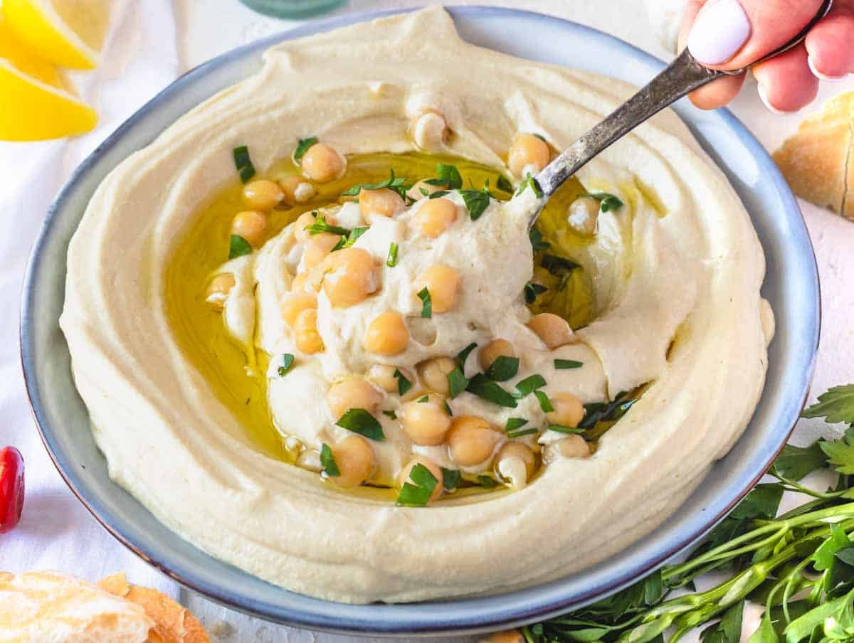 Hummus recipe with hand holding a silver spoon