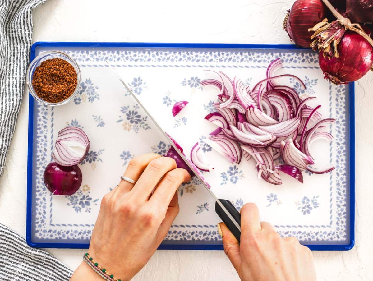 hands chopping red onions on a cutting board