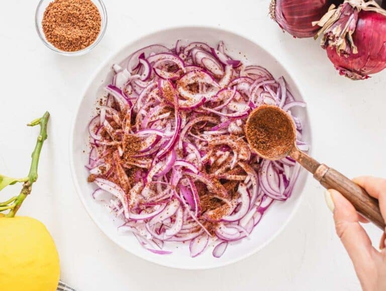 sliced red onions in a white bowl with sumac