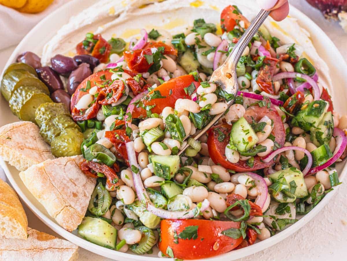 White bean salad with hand holding a silver fork