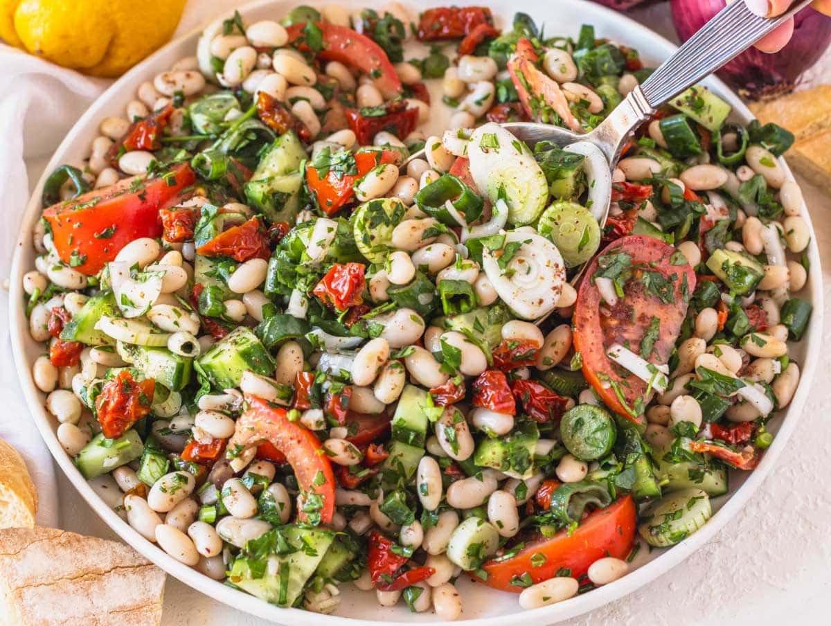 White bean salad on a plate with a silver spoon