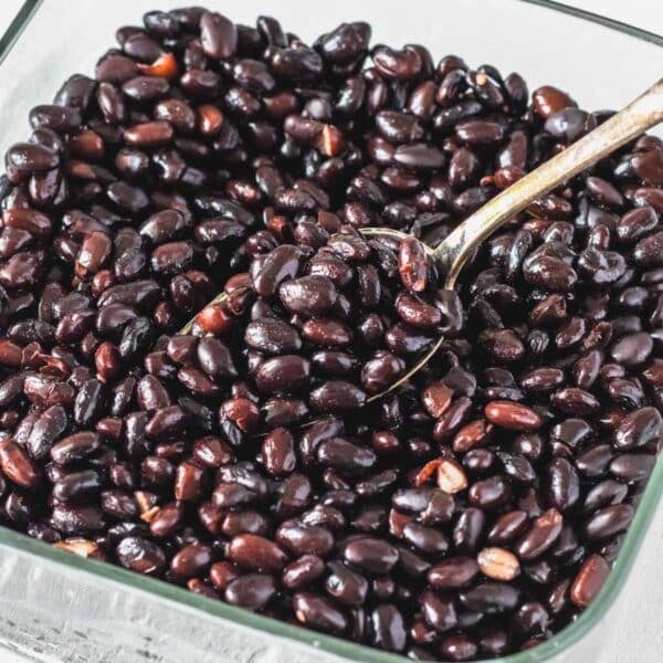 black beans in a glass container with a silver spoon