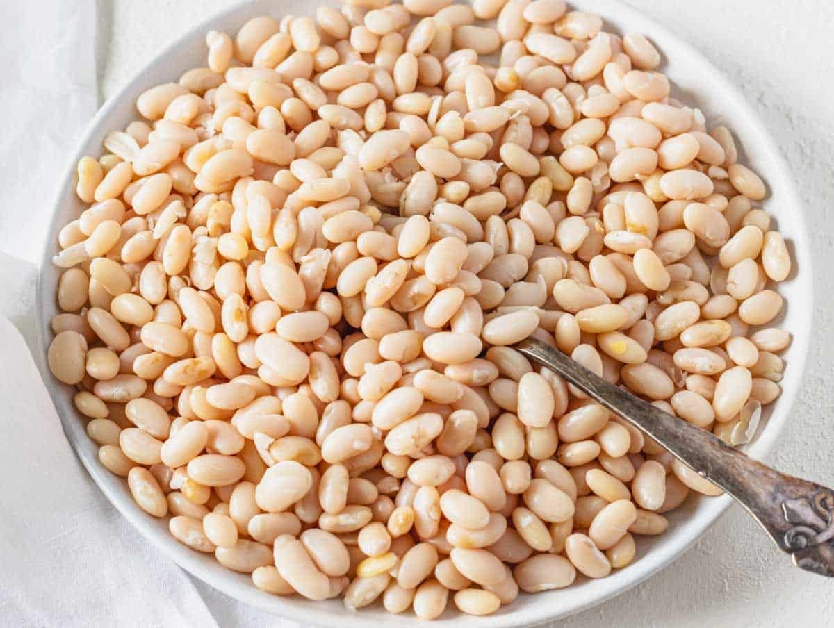 White beans after cooking on a white plate with a spoon