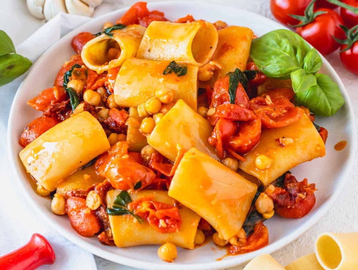 paccheri pasta on a white plate with chickpeas and basil