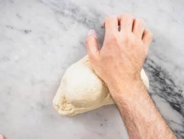 hand kneading pita dough on a worktop