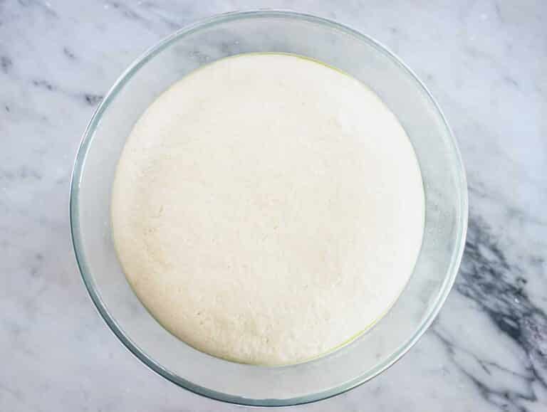 pita dough in a glass bowl after proofing