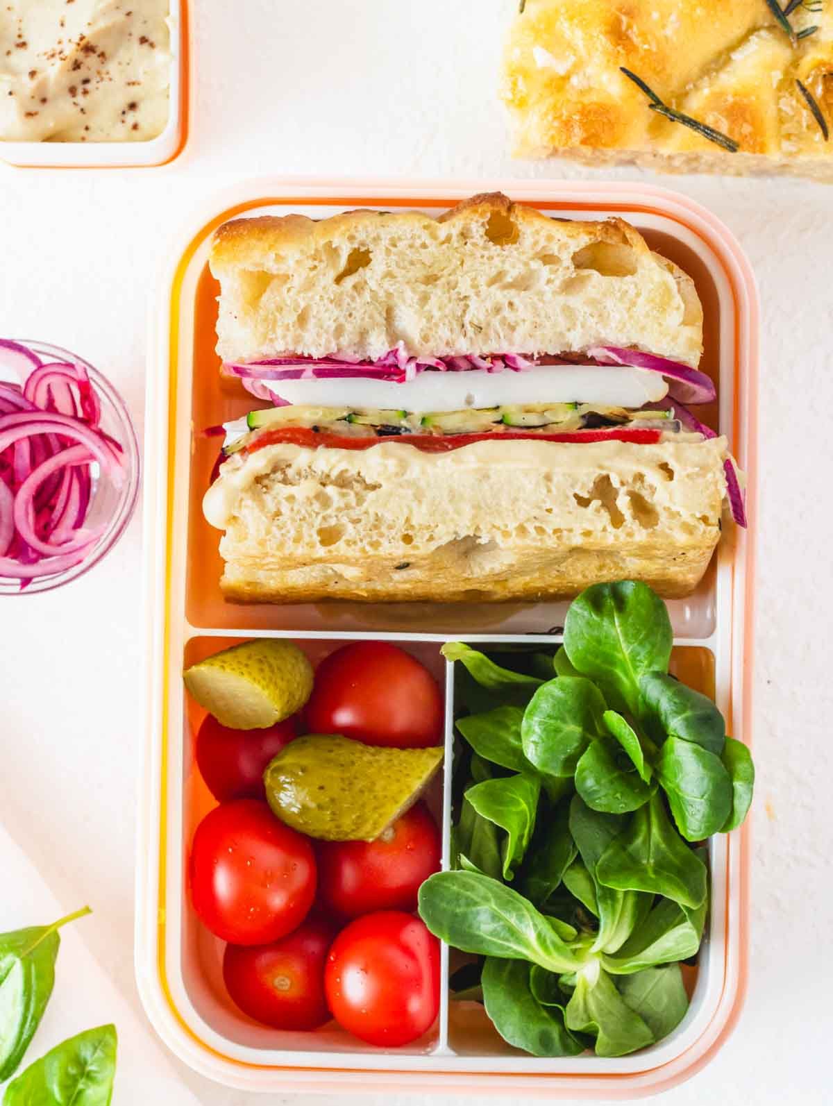 Focaccia sandwich in a bento box with salad and cherry tomatoes