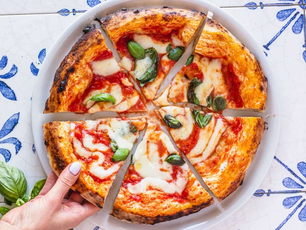 Neapolitan pizza on blue tiles with fresh basil