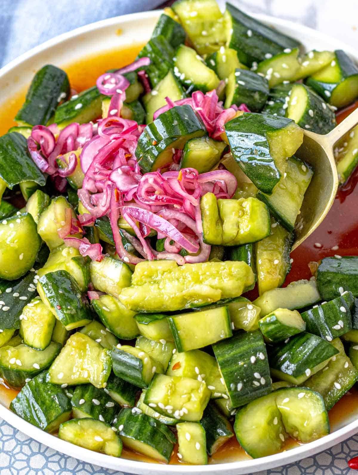 Asian cucumber salad on a white plate with pickled red onions