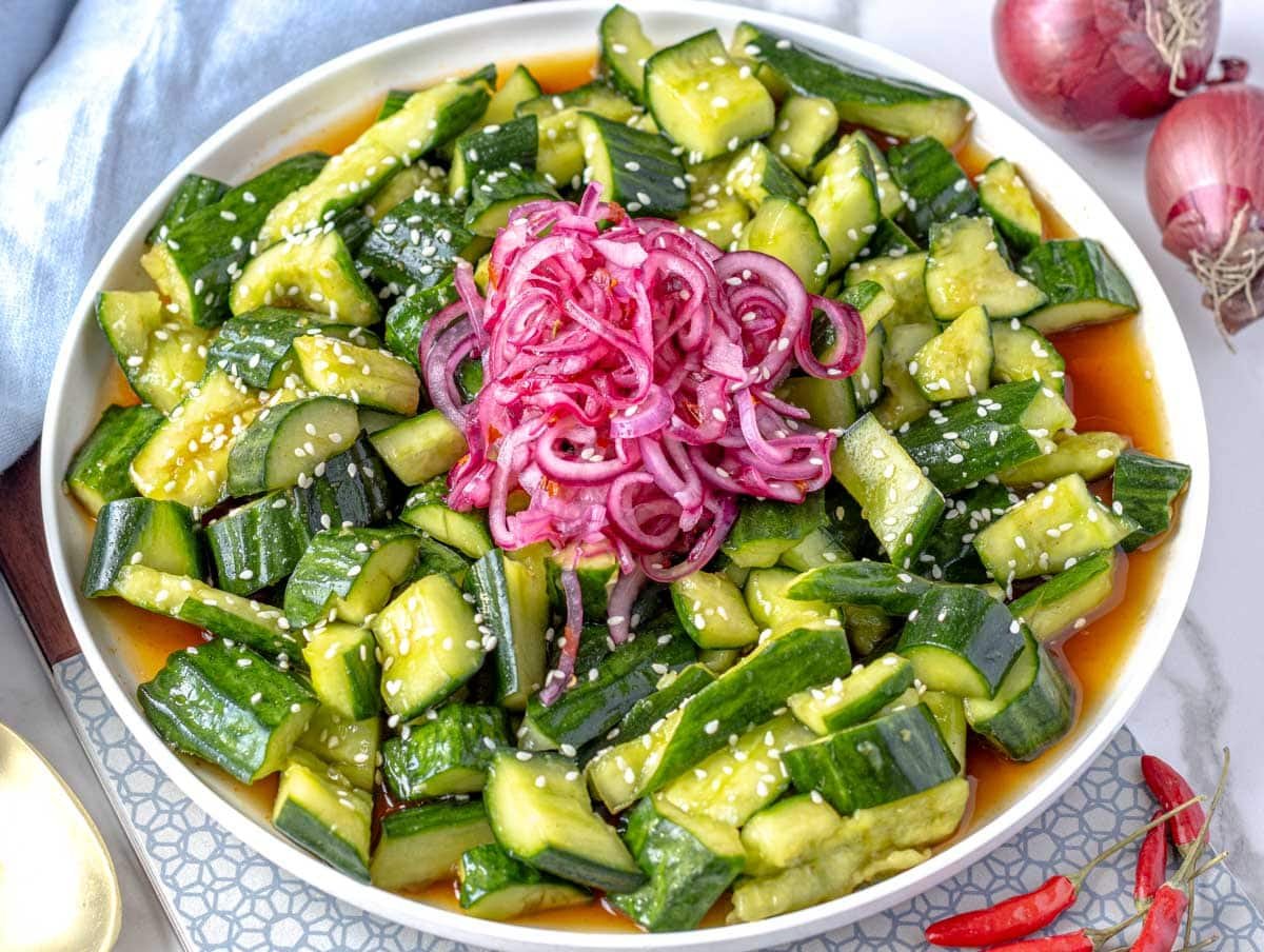 Asian cucumber salad with pickled onions on a white plate with sesame seeds