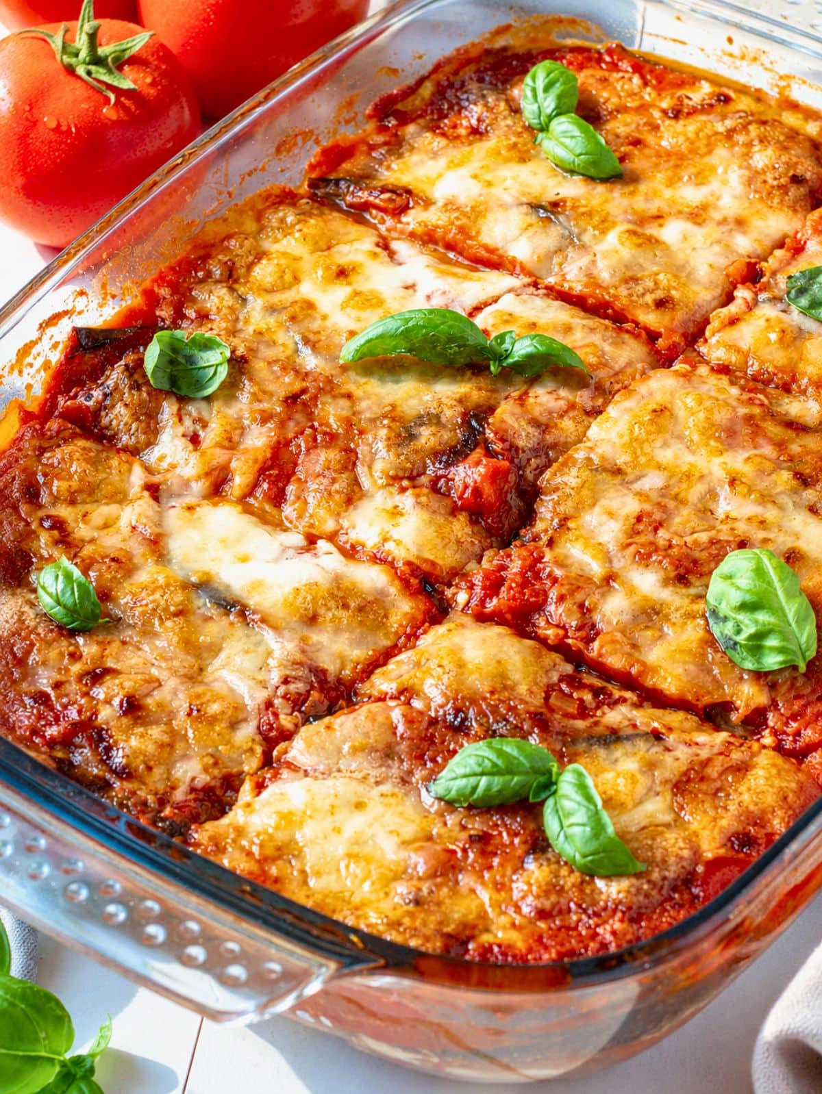 Baked Eggplant Parmigiana with golden mozzarella, tomato sauce, and fresh basil.