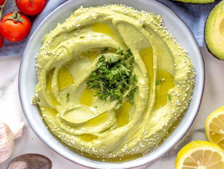 Creamy Avocado spread on a blue plate with lemon on the side