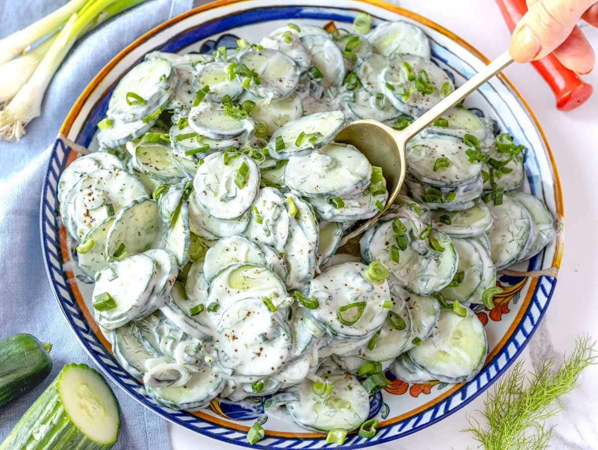 Creamy cucumber salad served with a golden spoon