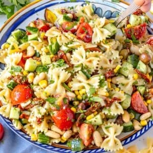 Easy pasta salad on a blue plate with hand holding a spoon