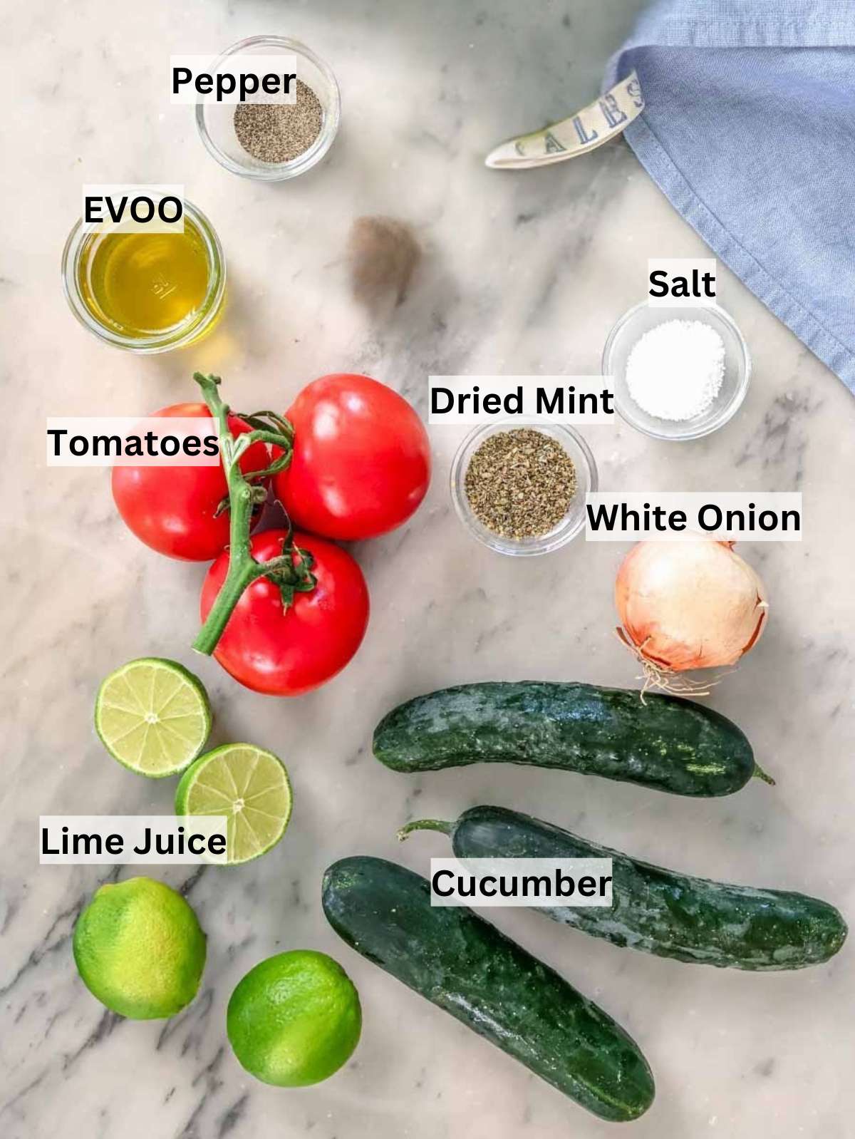 Ingredients for Shirazi salad such as cocumber tomato and onion on a marble table.