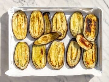 Step 2 Eggplant slices roasting until golden on parchment-lined baking trays.
