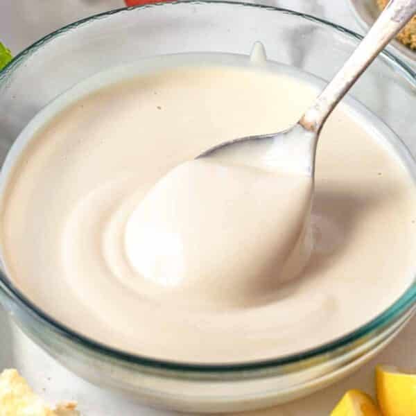Creamy tahini sauce in a glass bowl with a spoon
