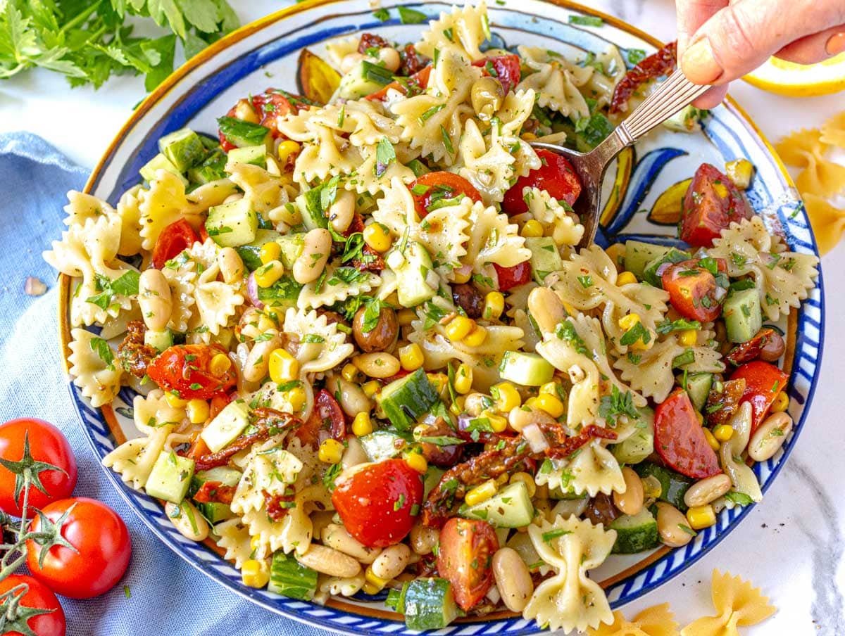 Vegan Pasta Salad with fresh parsley and hand serving the pasta salad