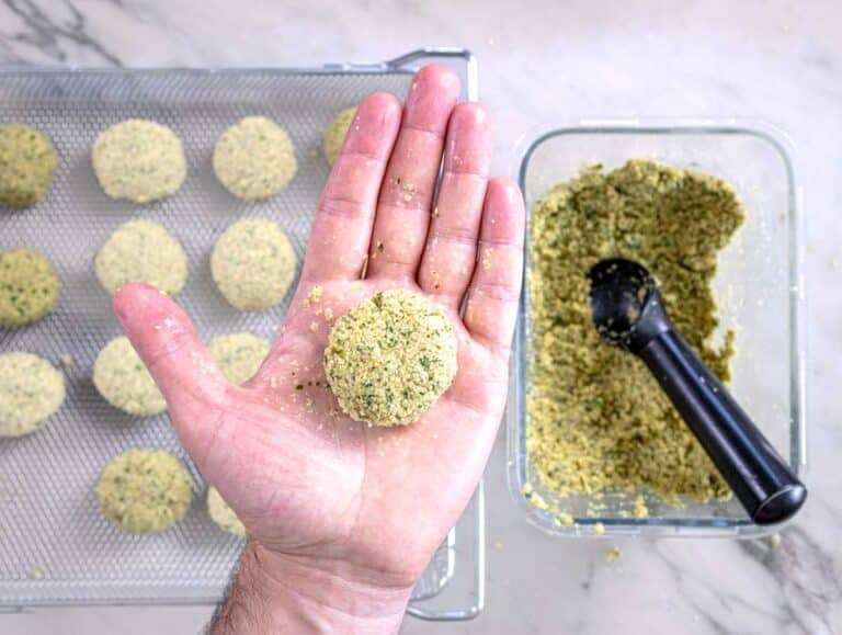 hands holding a falafel ball after shaping and flattening it