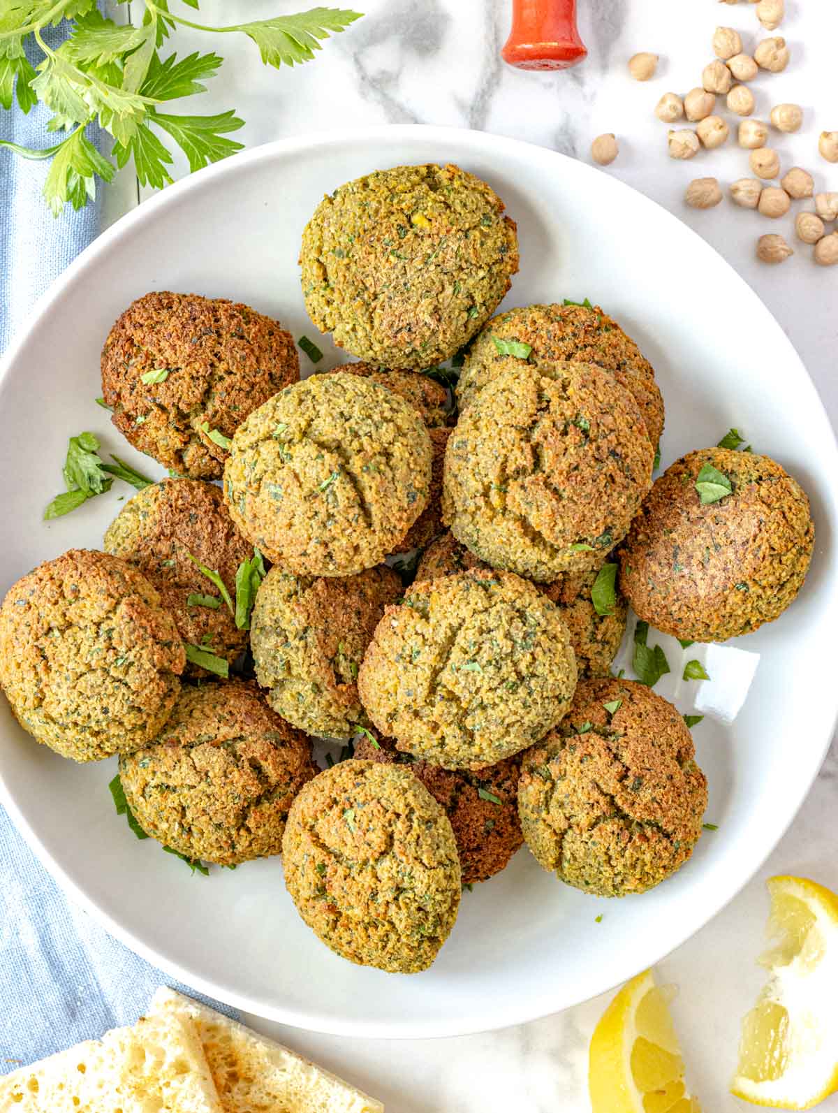 falafel ball on a white plate with fresh parsley and pita bread on the side