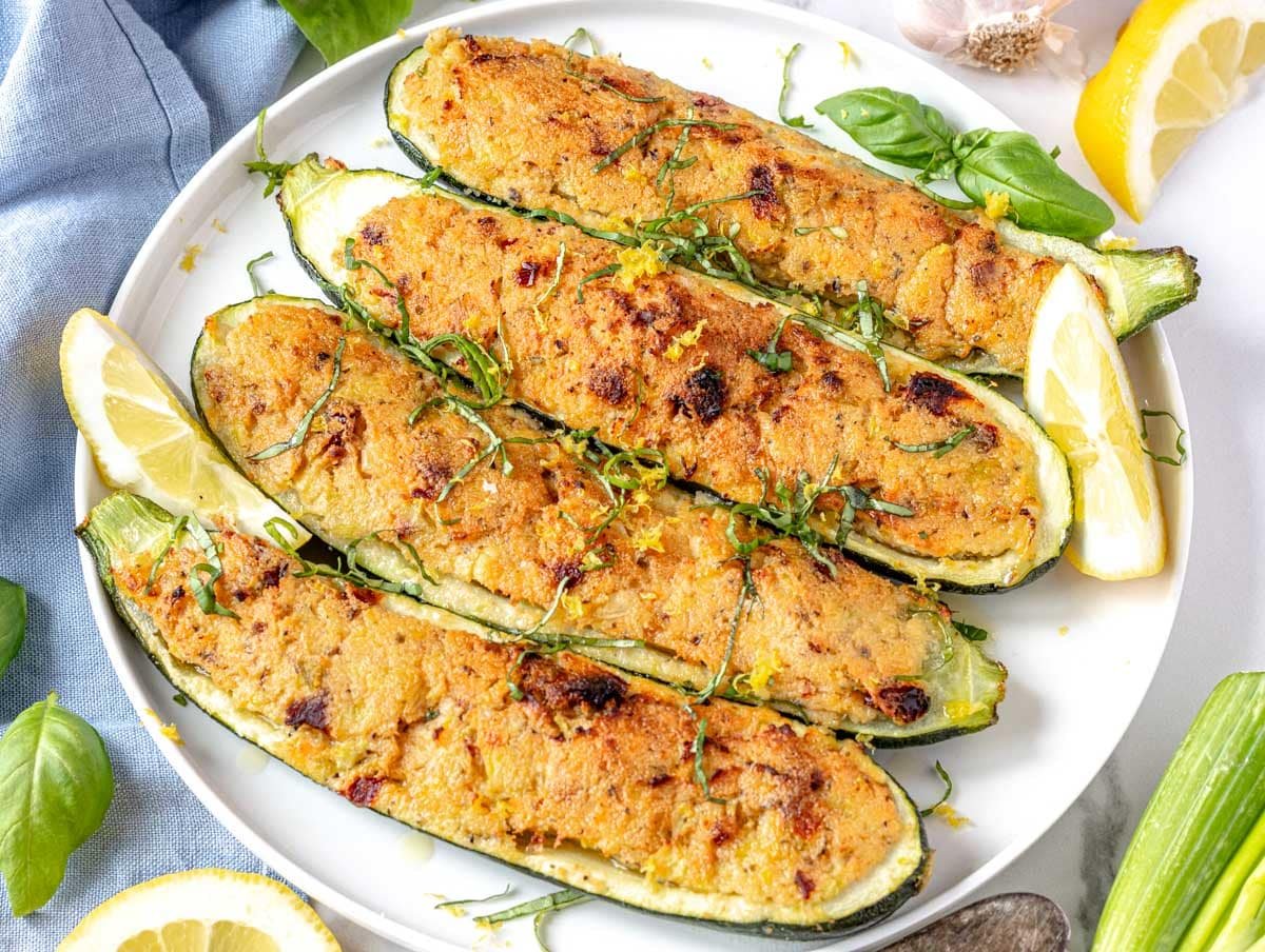 stuffed zucchini with ricotta served on a white plate with fresh basil