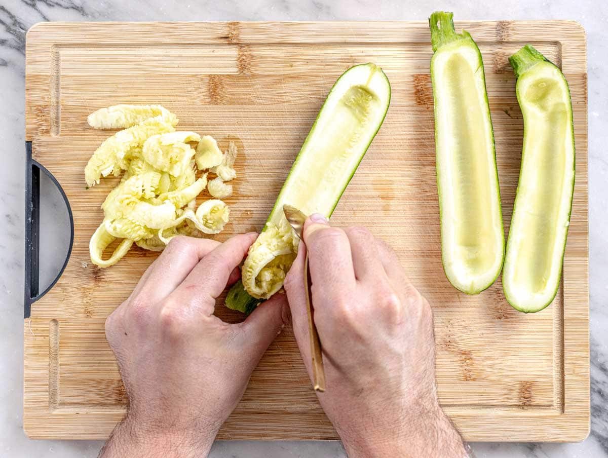 hands preparing zucchini for stuffing with a measuring spoon