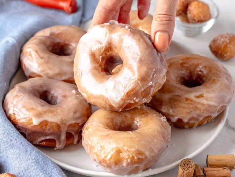 glazed donuts on a plate and a hand