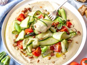 zucchini salad served on hummus with a fork
