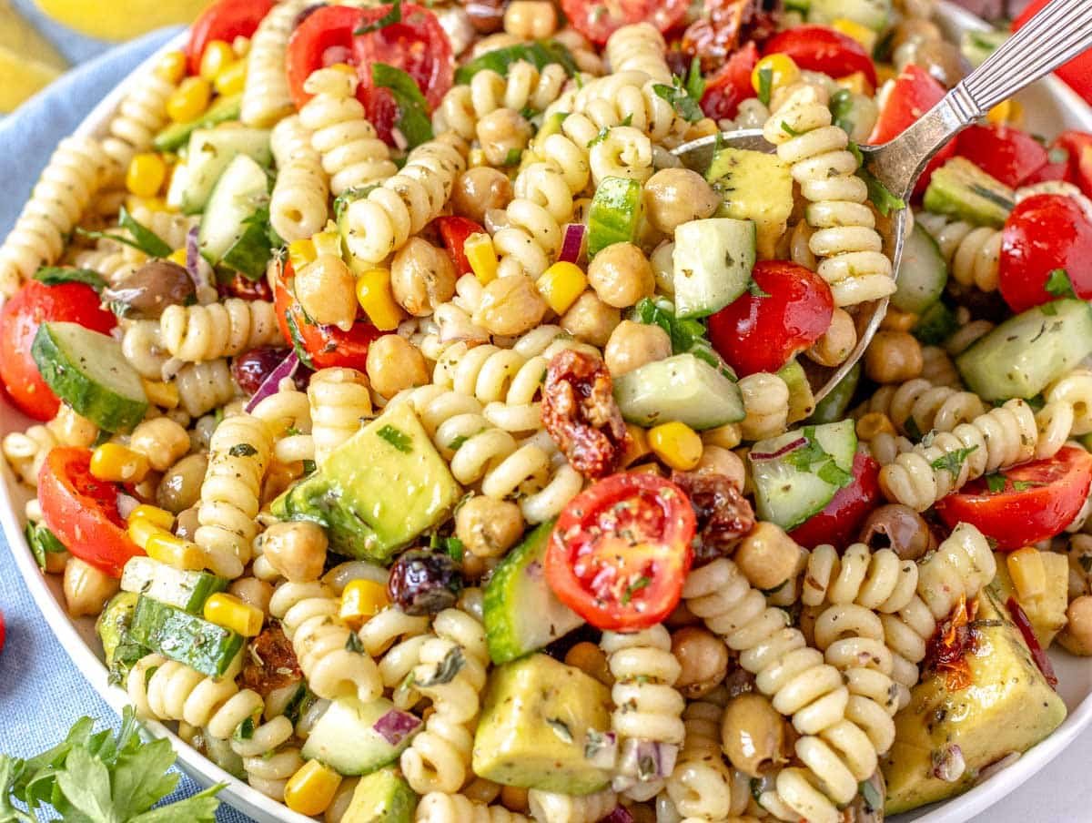 Chickpea Pasta Salad with a silver spoon and avocado cubes