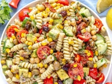 Chickpea Pasta Salad on a white plate with lemon wedges on the side