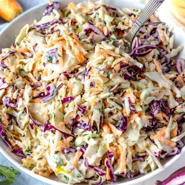 Creamy coleslaw in a white bowl with a silver spoon