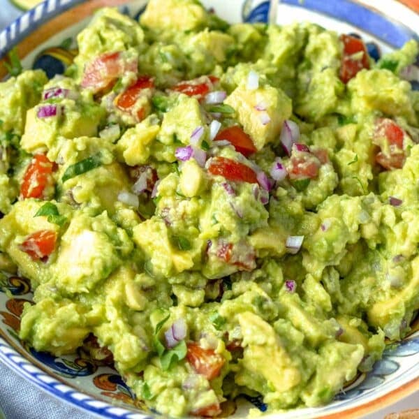 Guacamole with tomatoes and red onions in a blue bowl