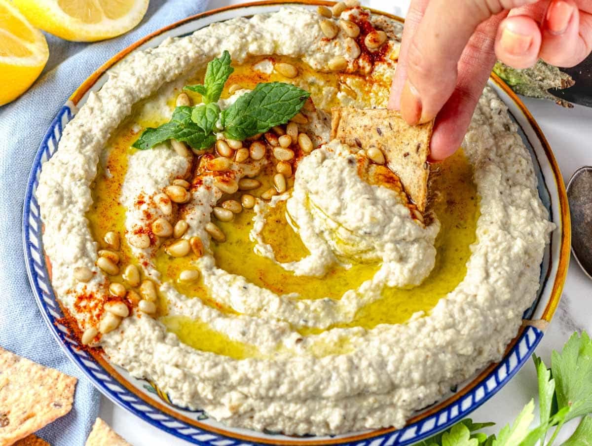Mutabal recipe with female hand dipping a sourdough cracker