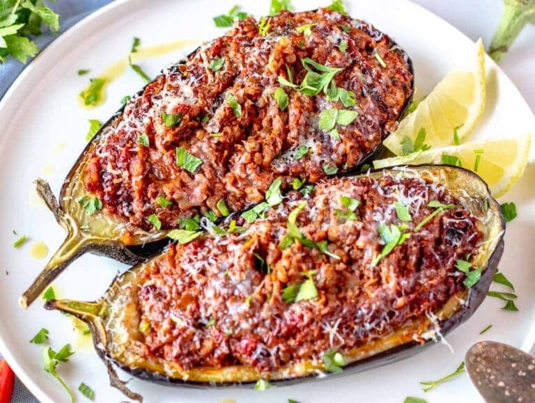 Stuffed eggplant with parmesan and fresh parsley on a white plate