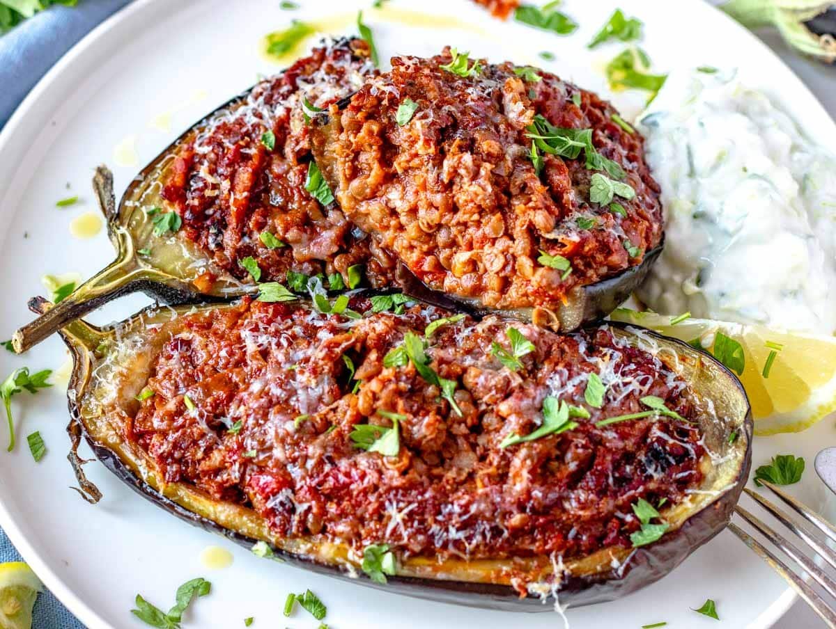 Stuffed eggplant cut open on a plate with tzatziki