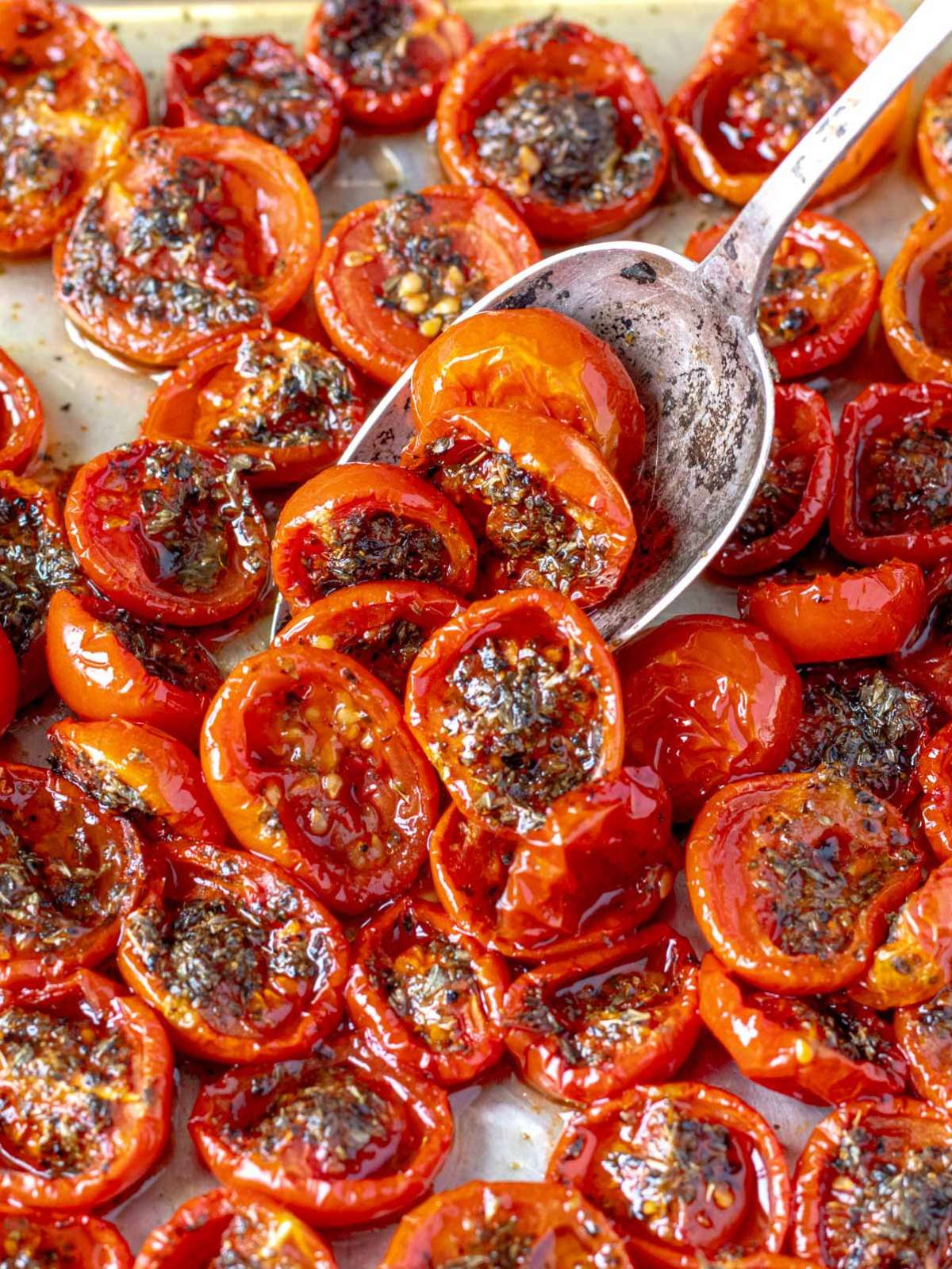 Tomato confit with caramelized tomatoes, basil, and glossy olive oil on white marble.